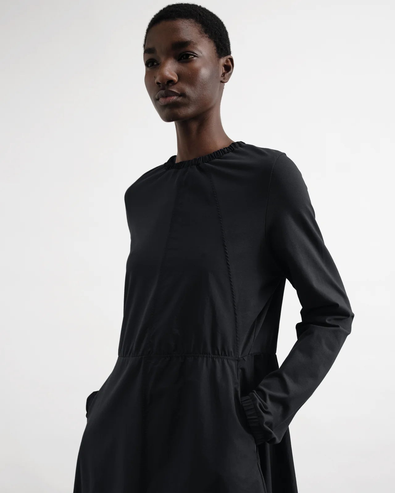 Person wearing a black dress against a white background