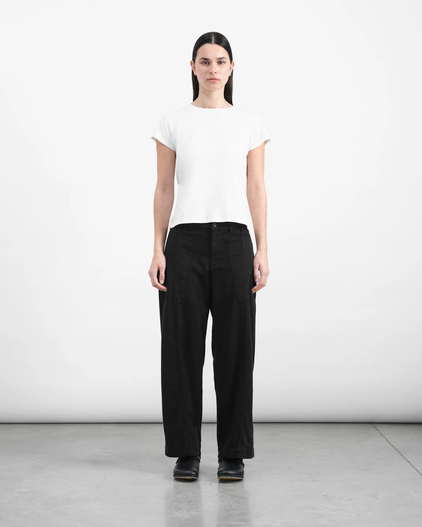 Person wearing a white t-shirt and black pants on a plain background