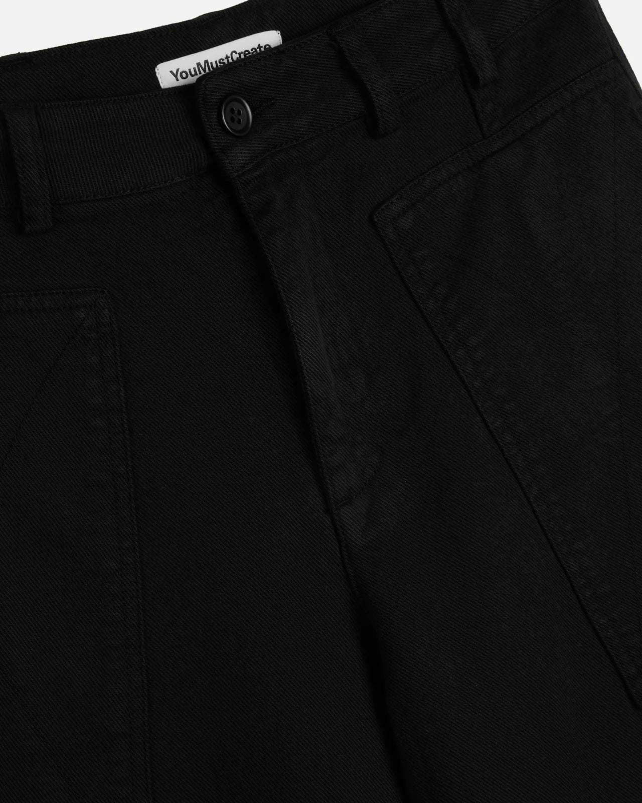 Close-up of black pants with a brand label on a white background