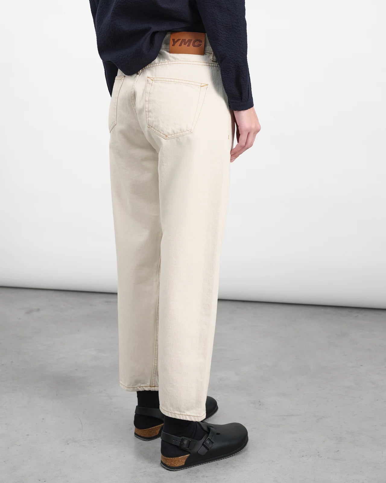 Person wearing beige pants and black shoes on a plain background