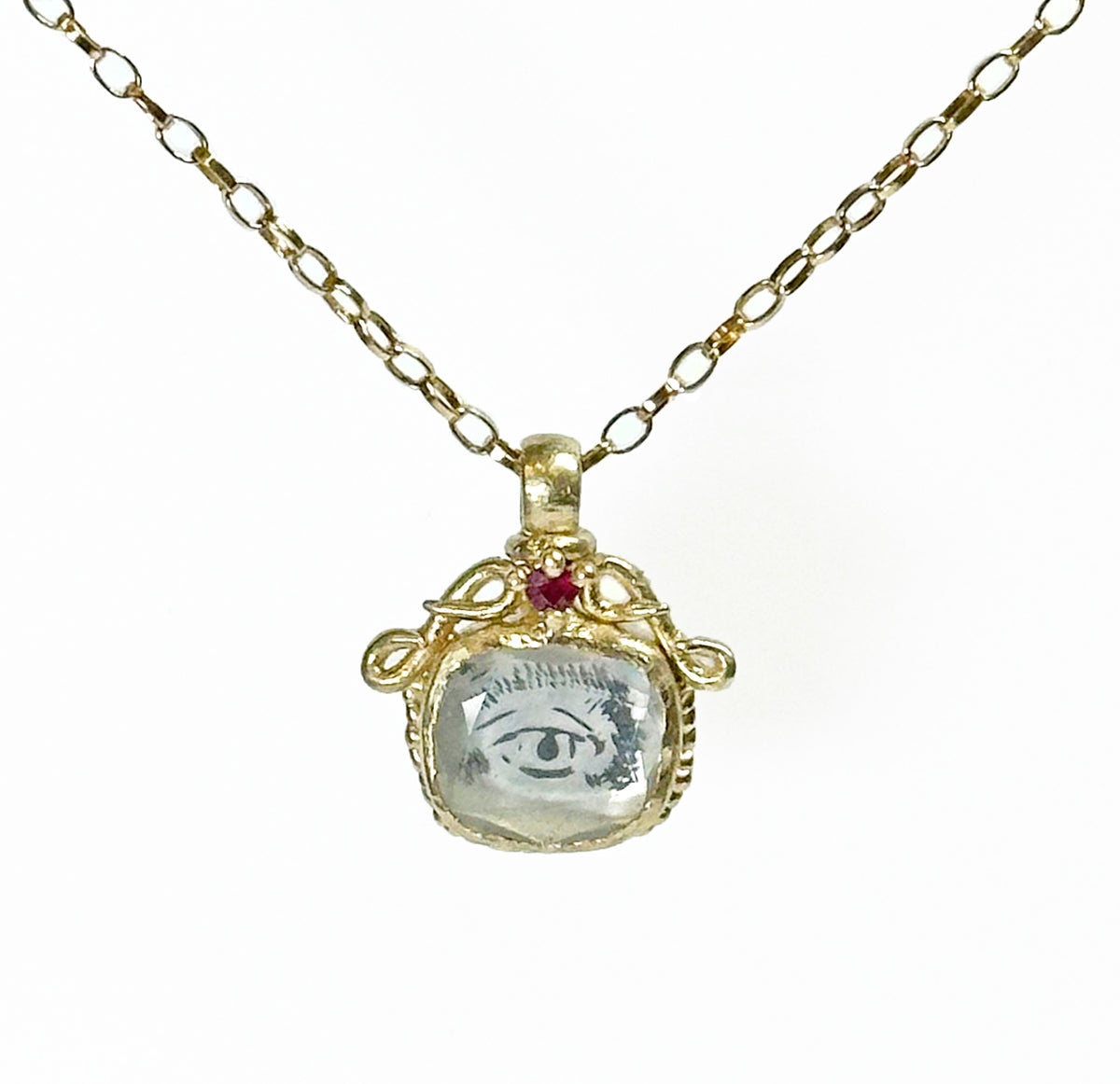 A yellow gold necklace featuring a pendant with a human eye design and a ruby.
