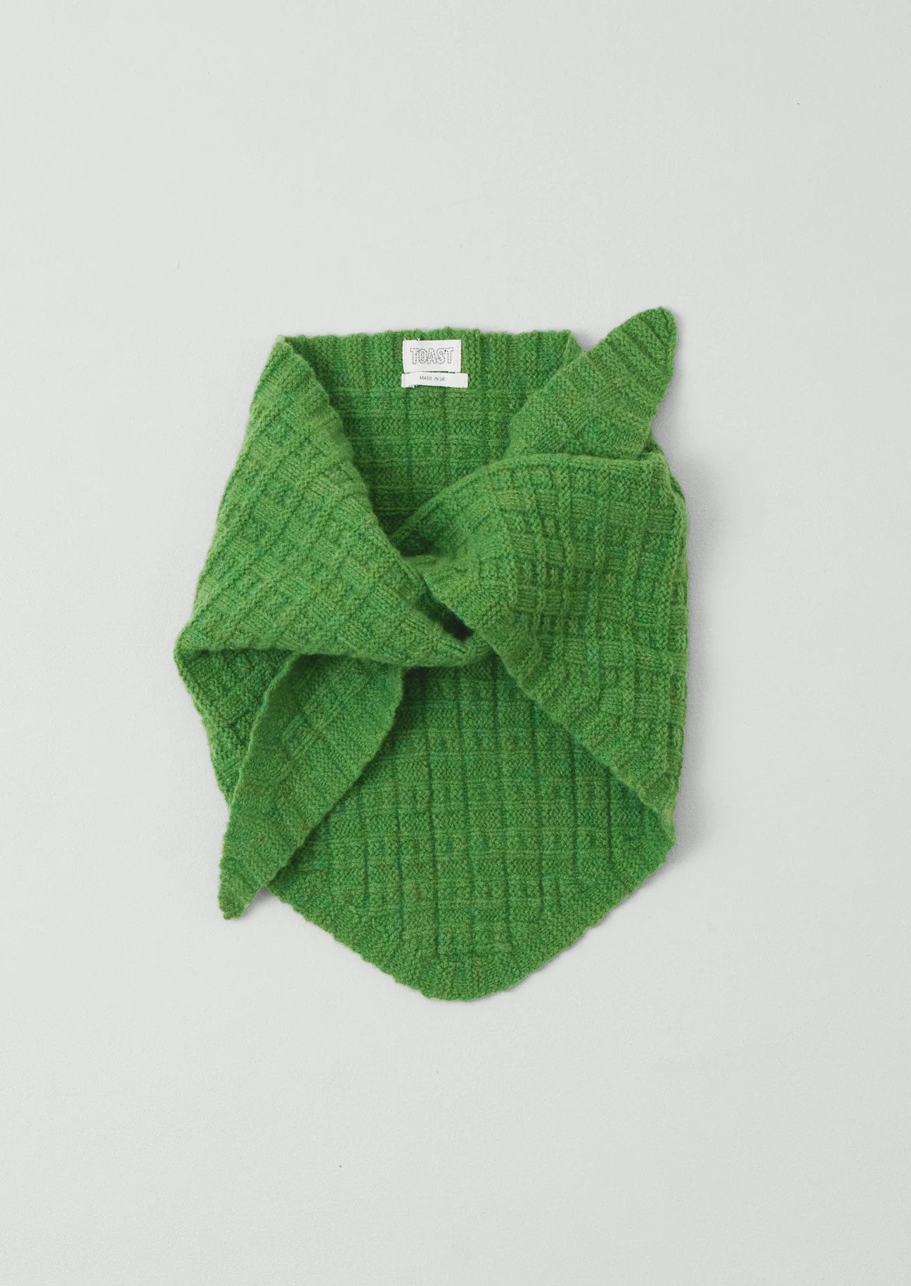 Green knitted scarf on a light gray background