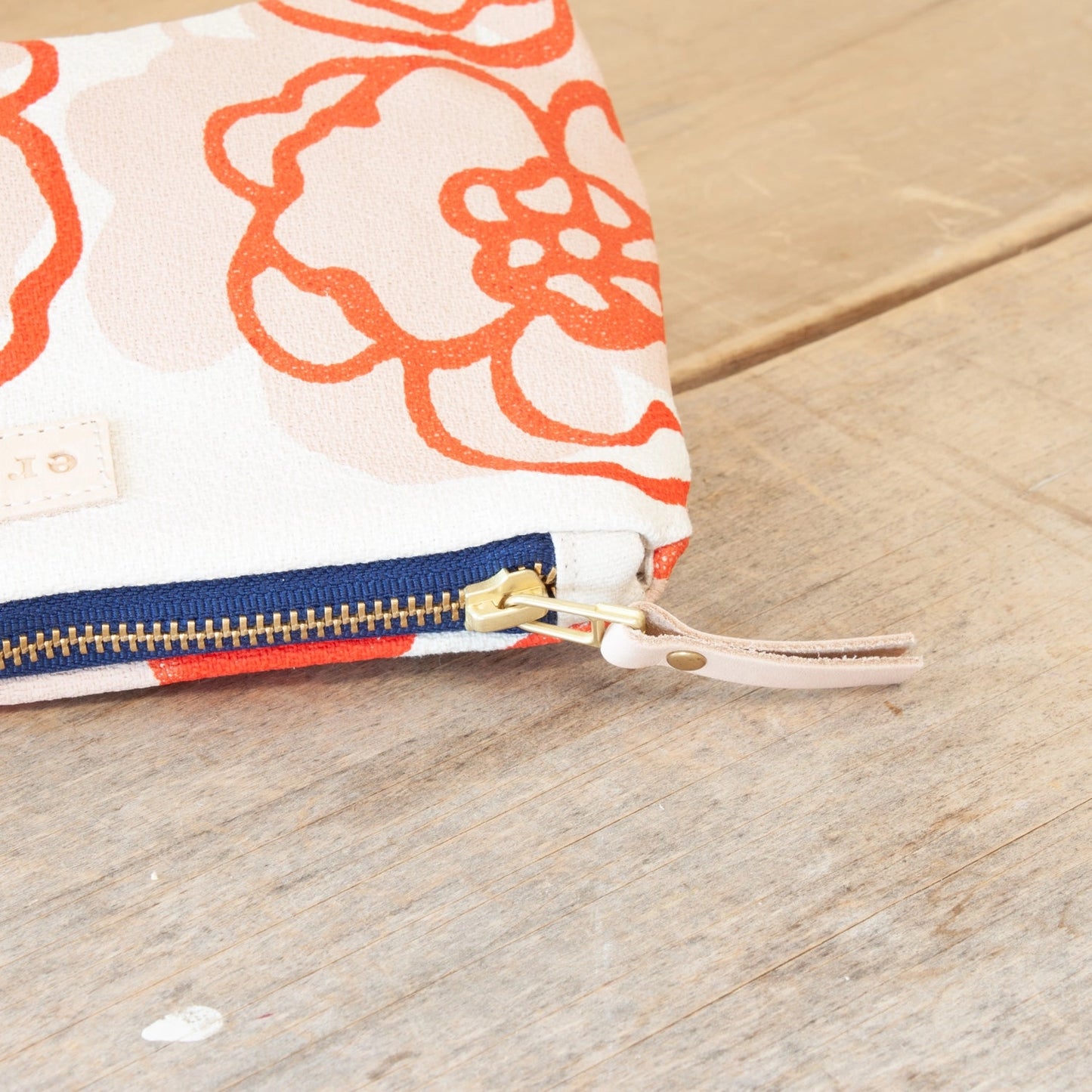 Close-up of a pouch with a floral pattern and zipper on a wooden surface