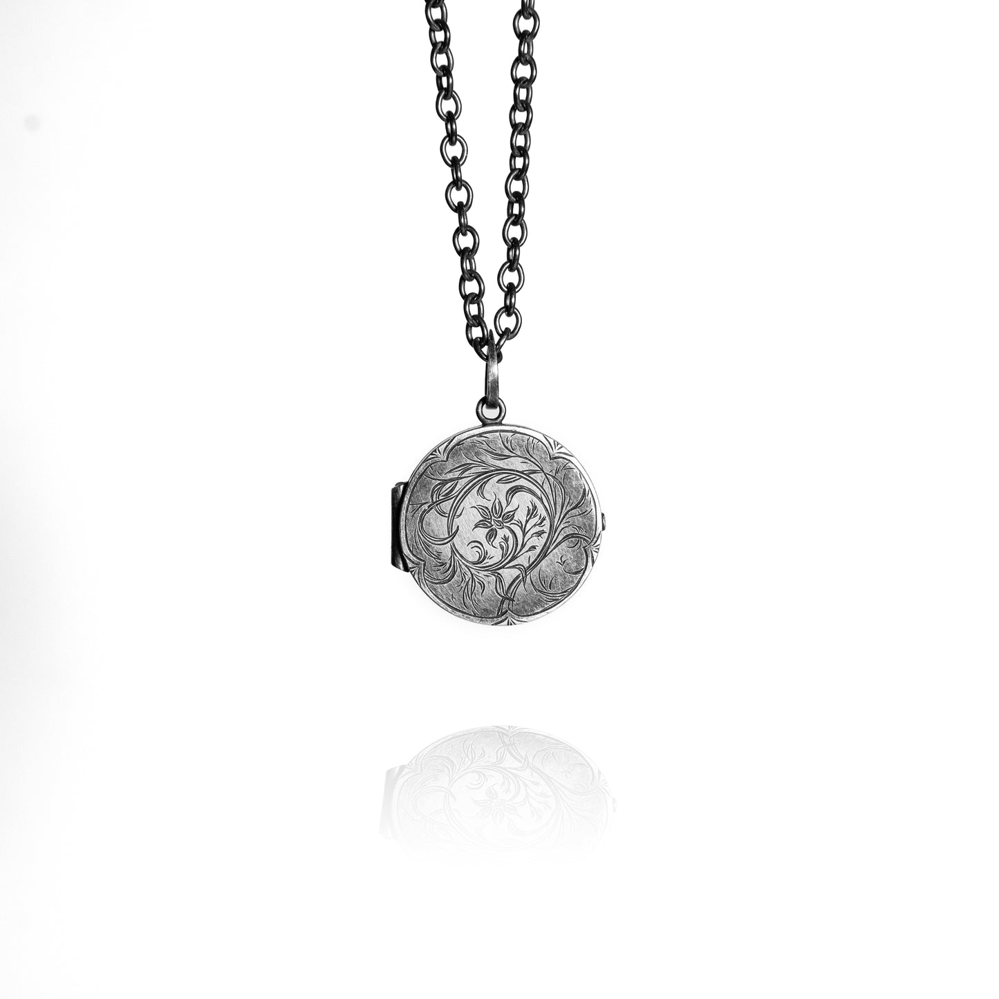 Silver locket with intricate design on a chain against a white background