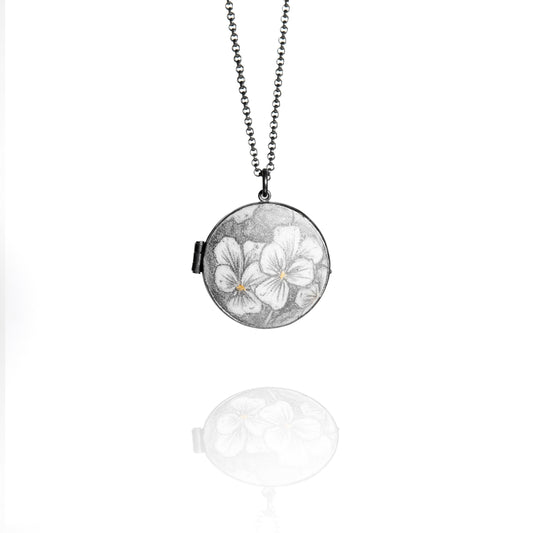 Necklace with a round locket featuring floral design on a white background
