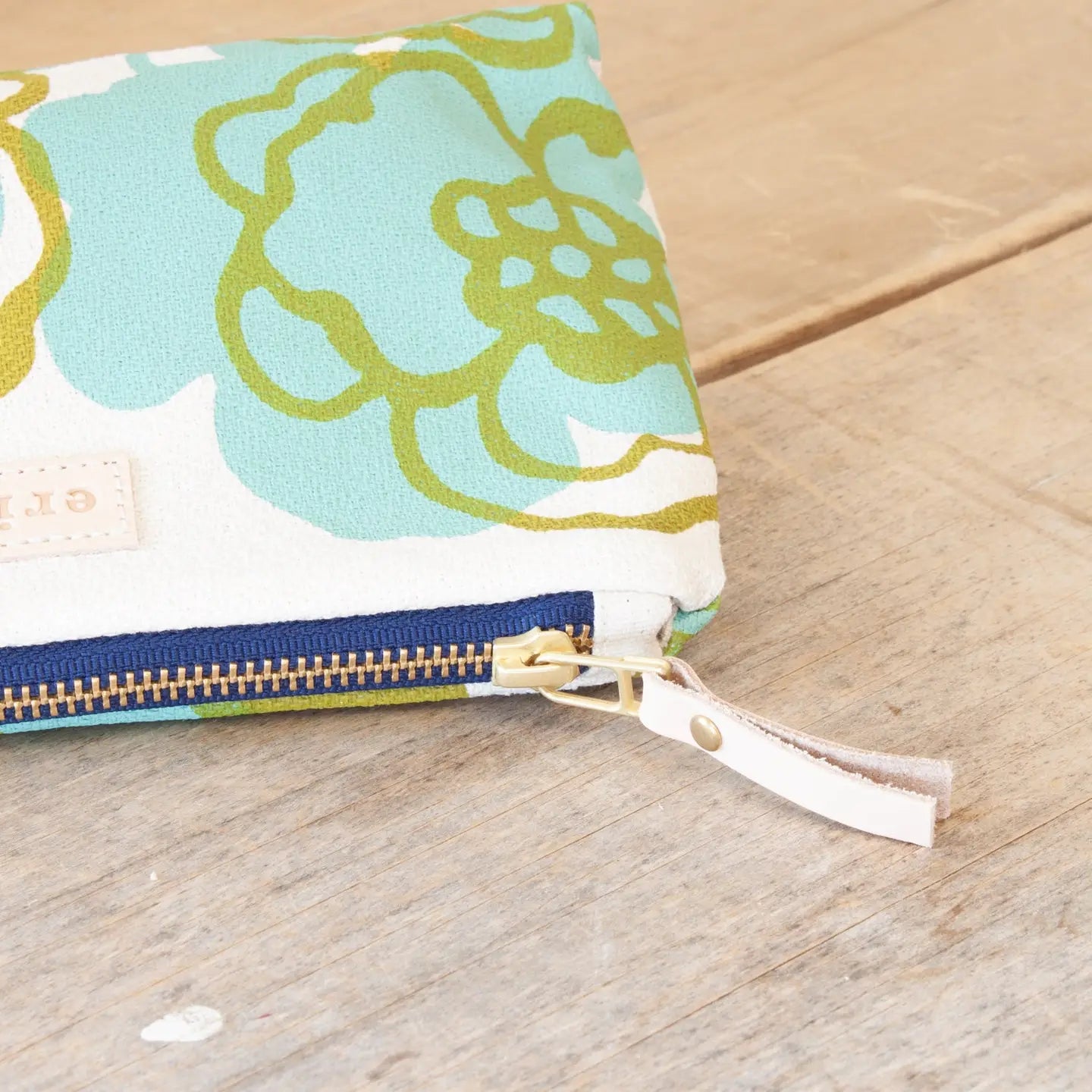 Fabric pouch with green floral pattern on a wooden surface