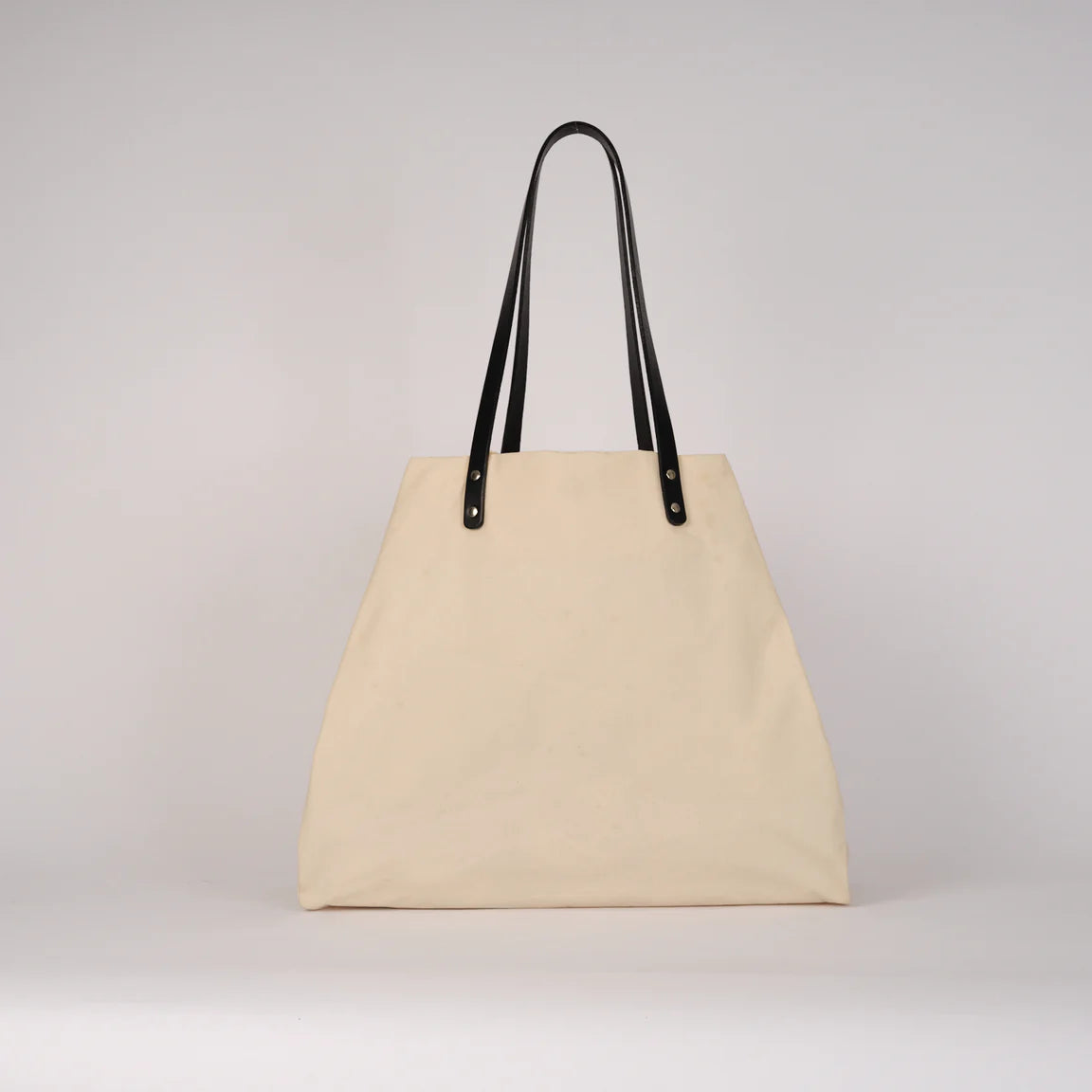 Beige tote bag with black handles on a light gray background