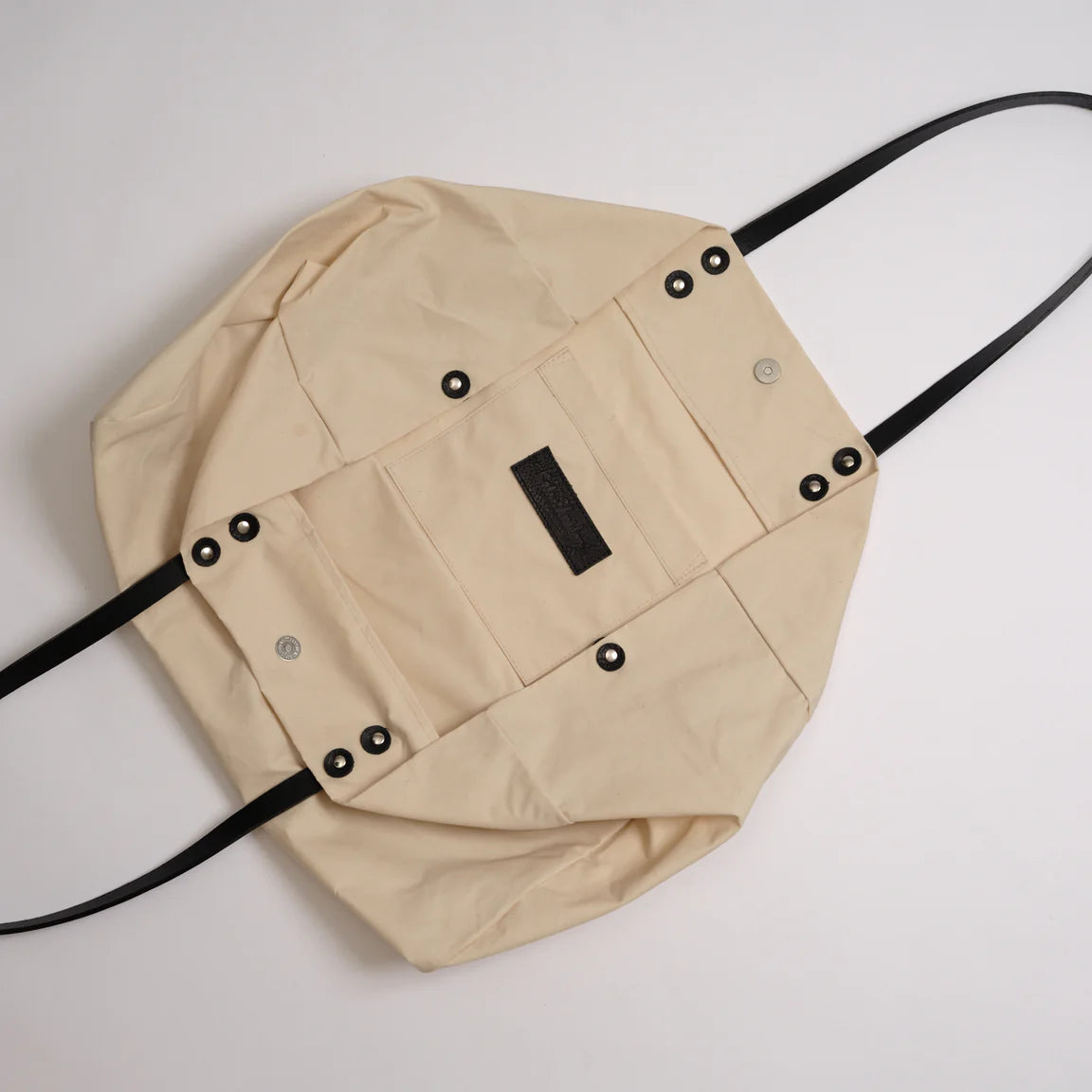 Beige backpack with black straps on a white background