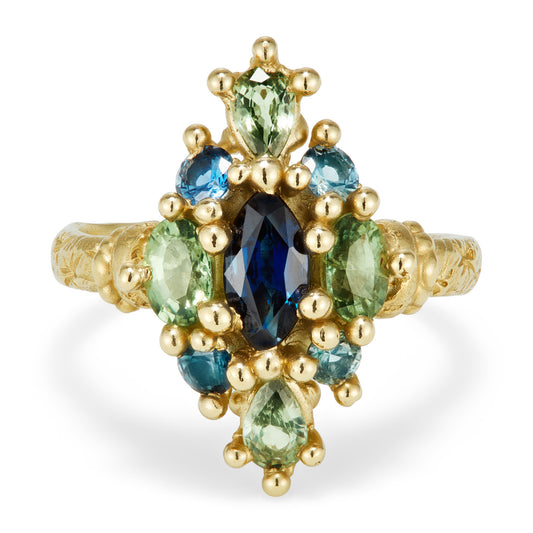 A yellow gold ring in a north-south kite shape with a mix of blue and green sapphires.
