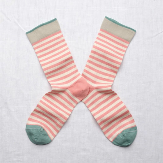 Pair of pink and beige striped socks with green toes and cuffs on a light gray background
