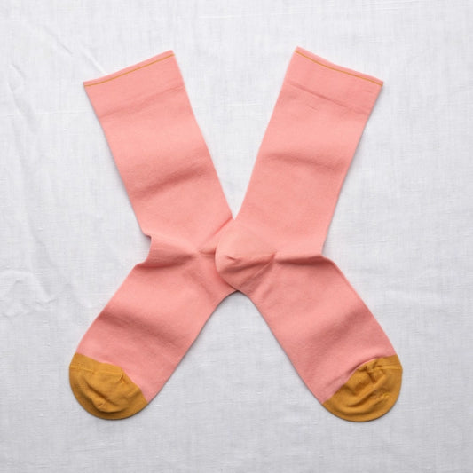 Pair of pink socks with yellow toes and heels on a light gray background