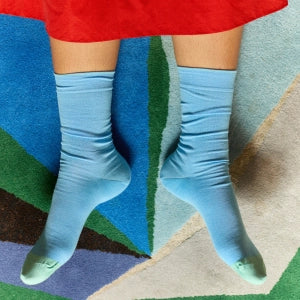 Blue knee-high socks worn by a person on a colorful geometric-patterned rug.