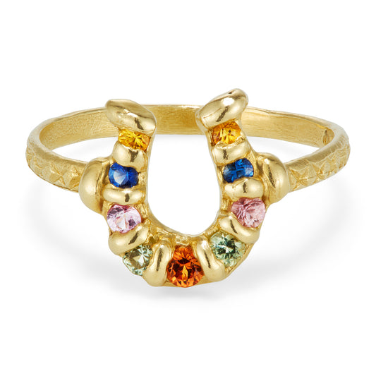 A yellow gold ring with a horseshoe embellished with colored sapphires.