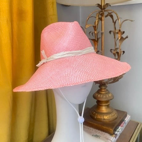 Pink handwoven straw hat with white straw ribbon and leather tie