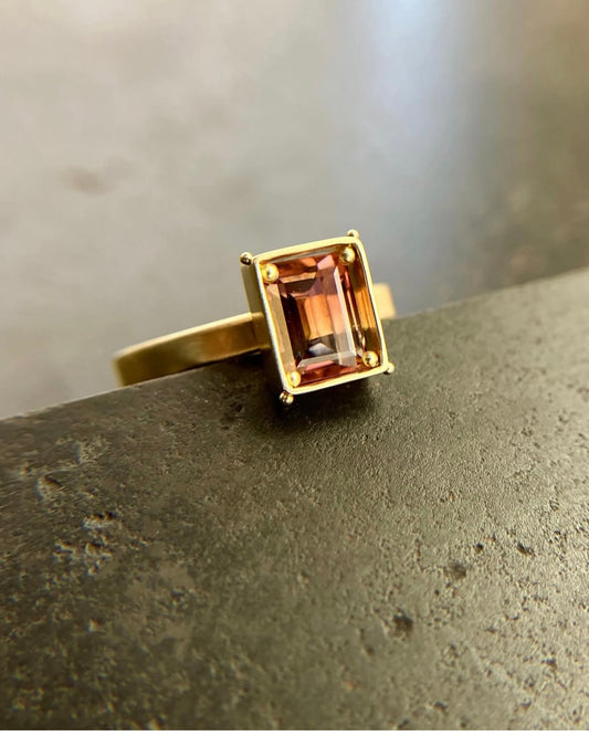 A rectangular pink ombre tourmaline stone ring in gold setting.
