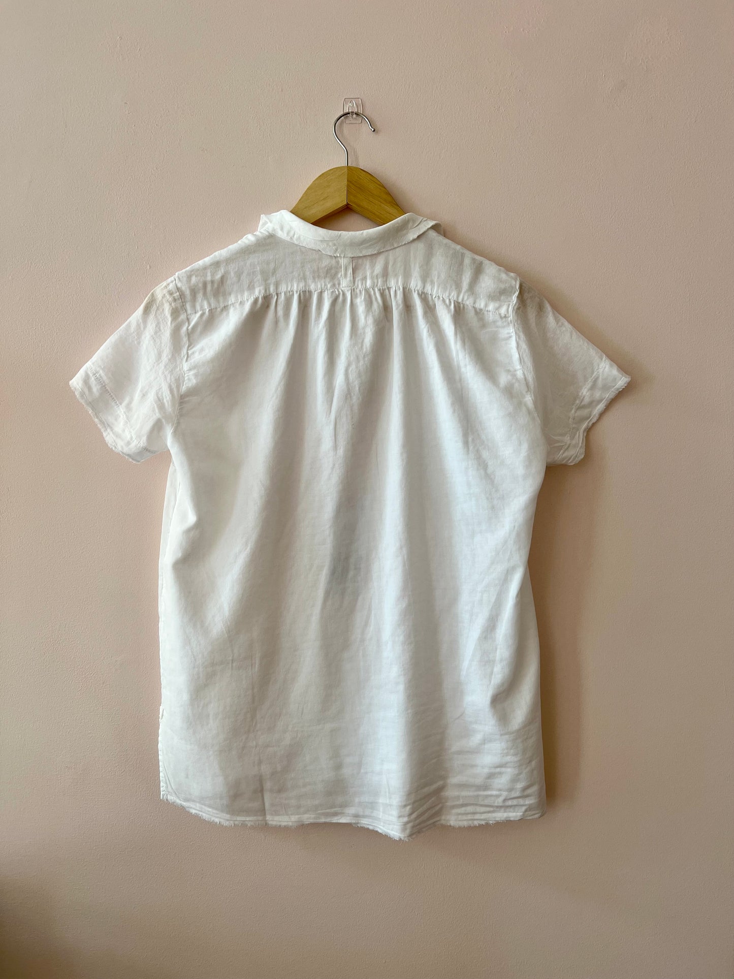White shirt on a hanger against a beige wall
