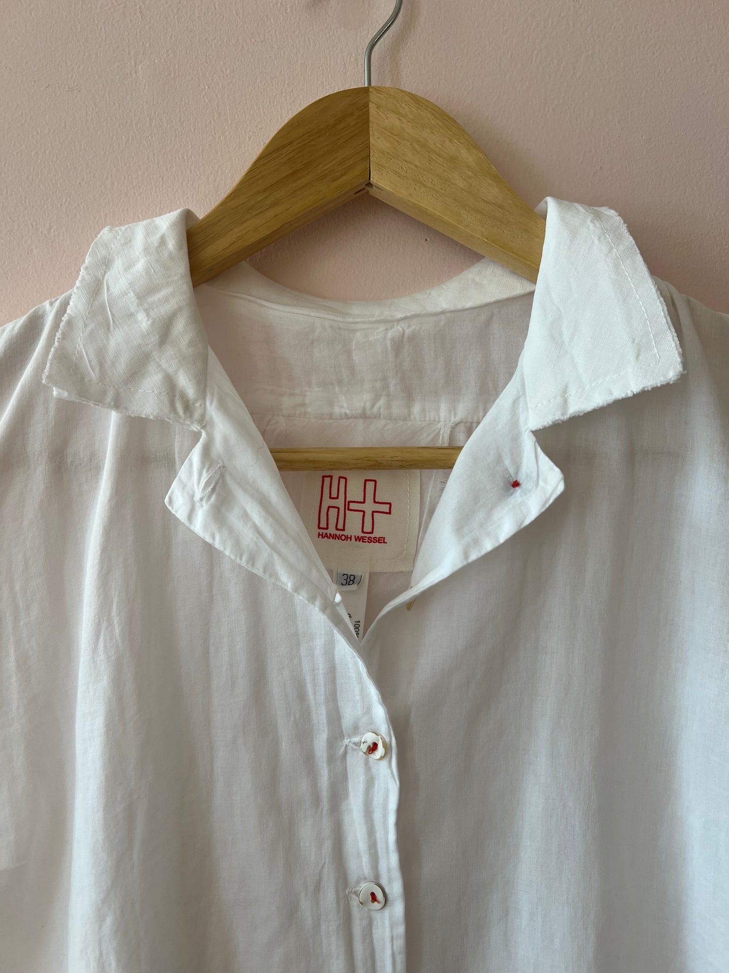 White shirt on a wooden hanger with a beige background