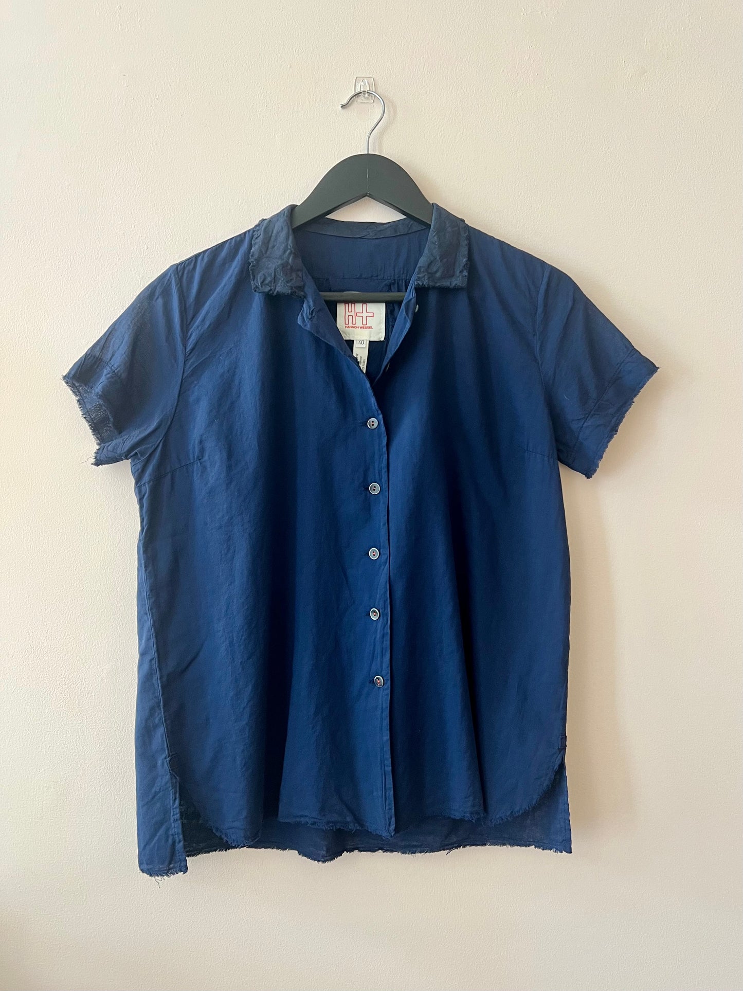 Short sleeve blue shirt with open collar on beige background