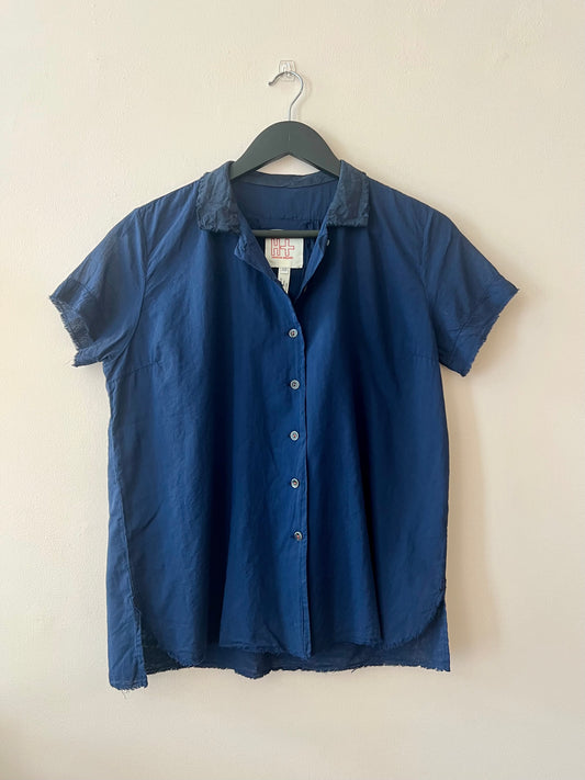 Short sleeve blue shirt with open collar on beige background