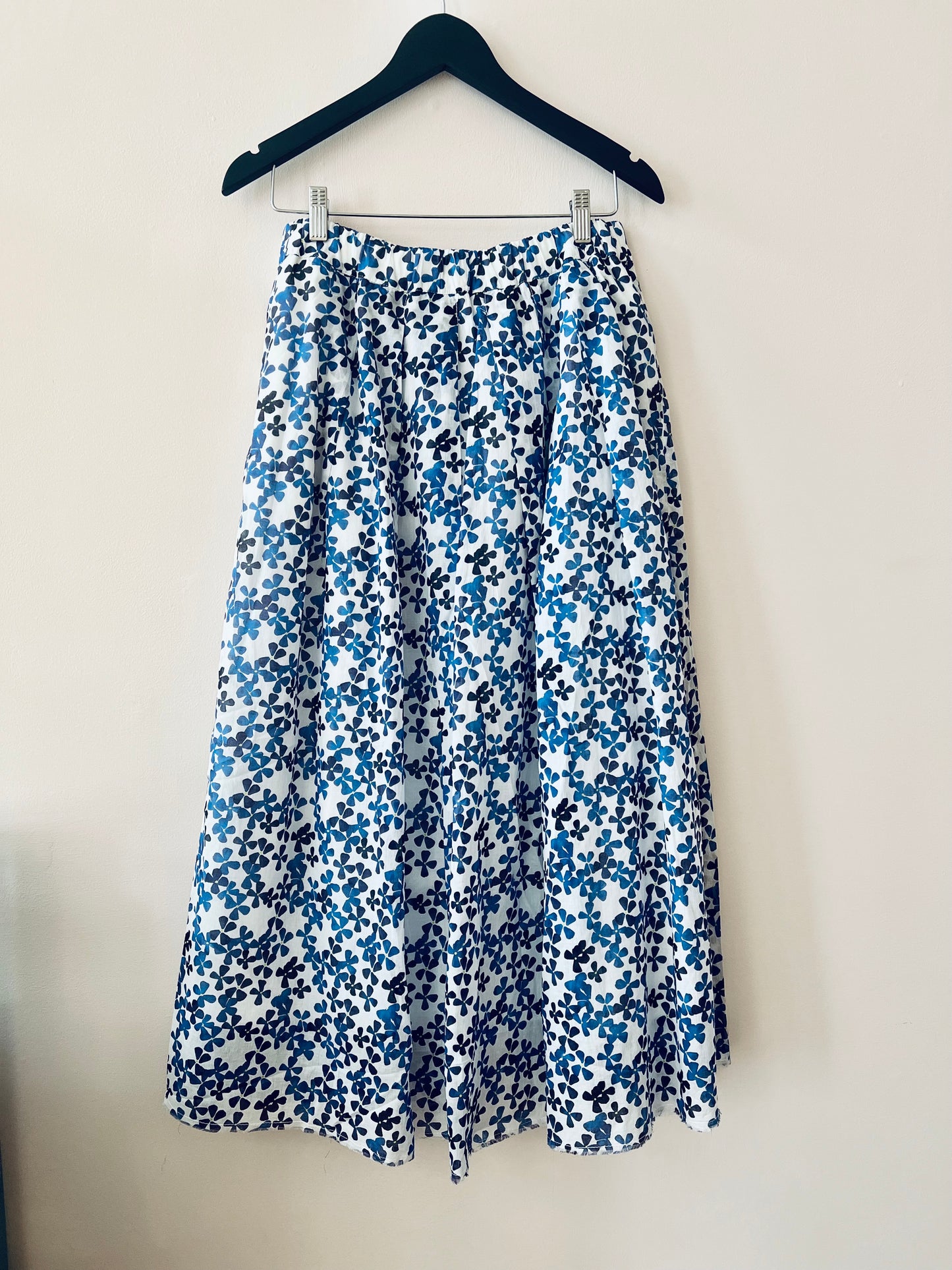 Floral skirt with blue and white pattern on a hanger against a plain background