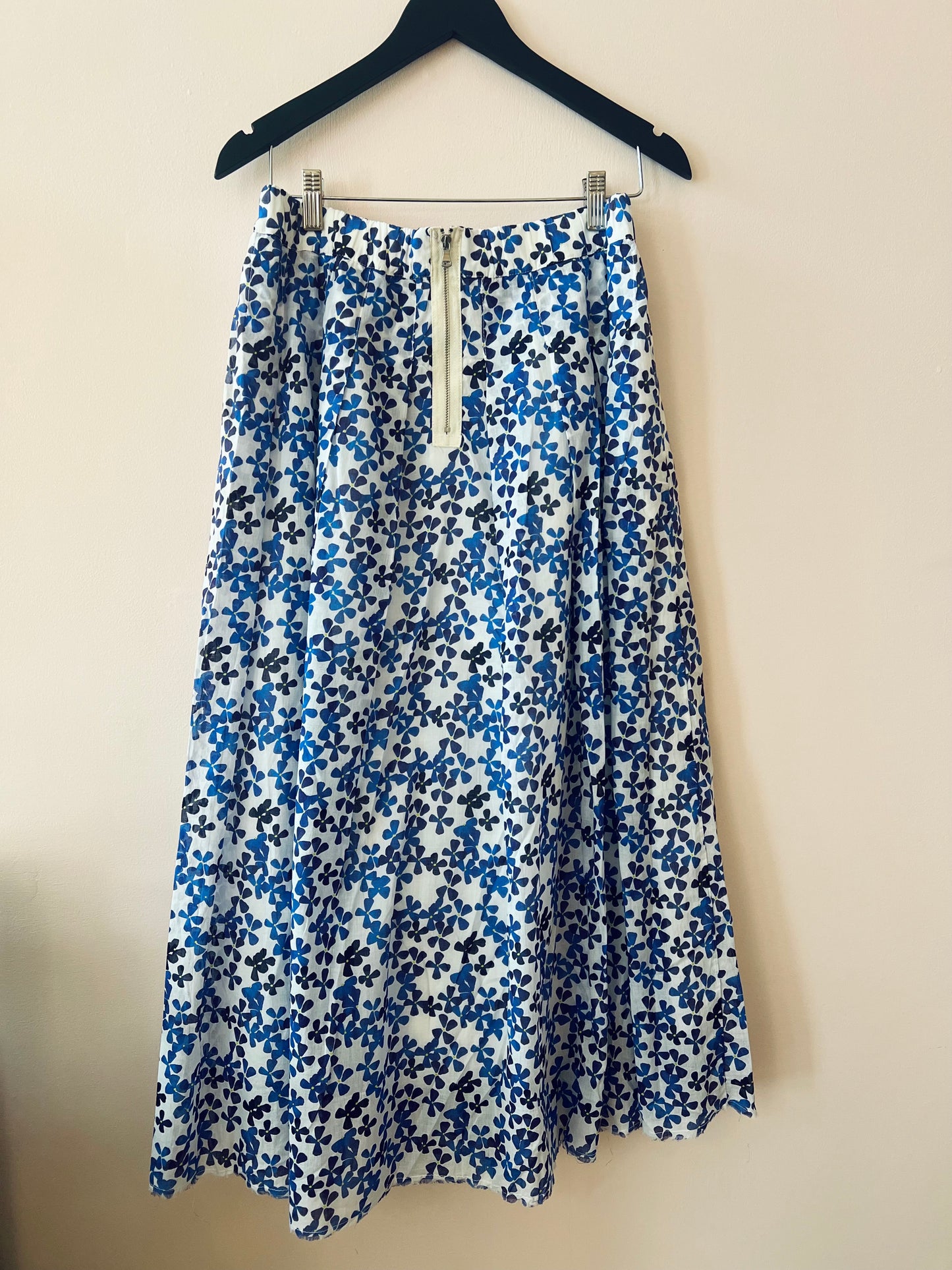 Blue and white floral skirt on a hanger against a beige background