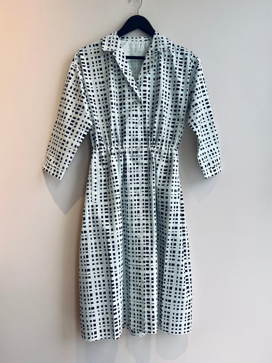 Black and white checkered dress on a hanger against a plain background
