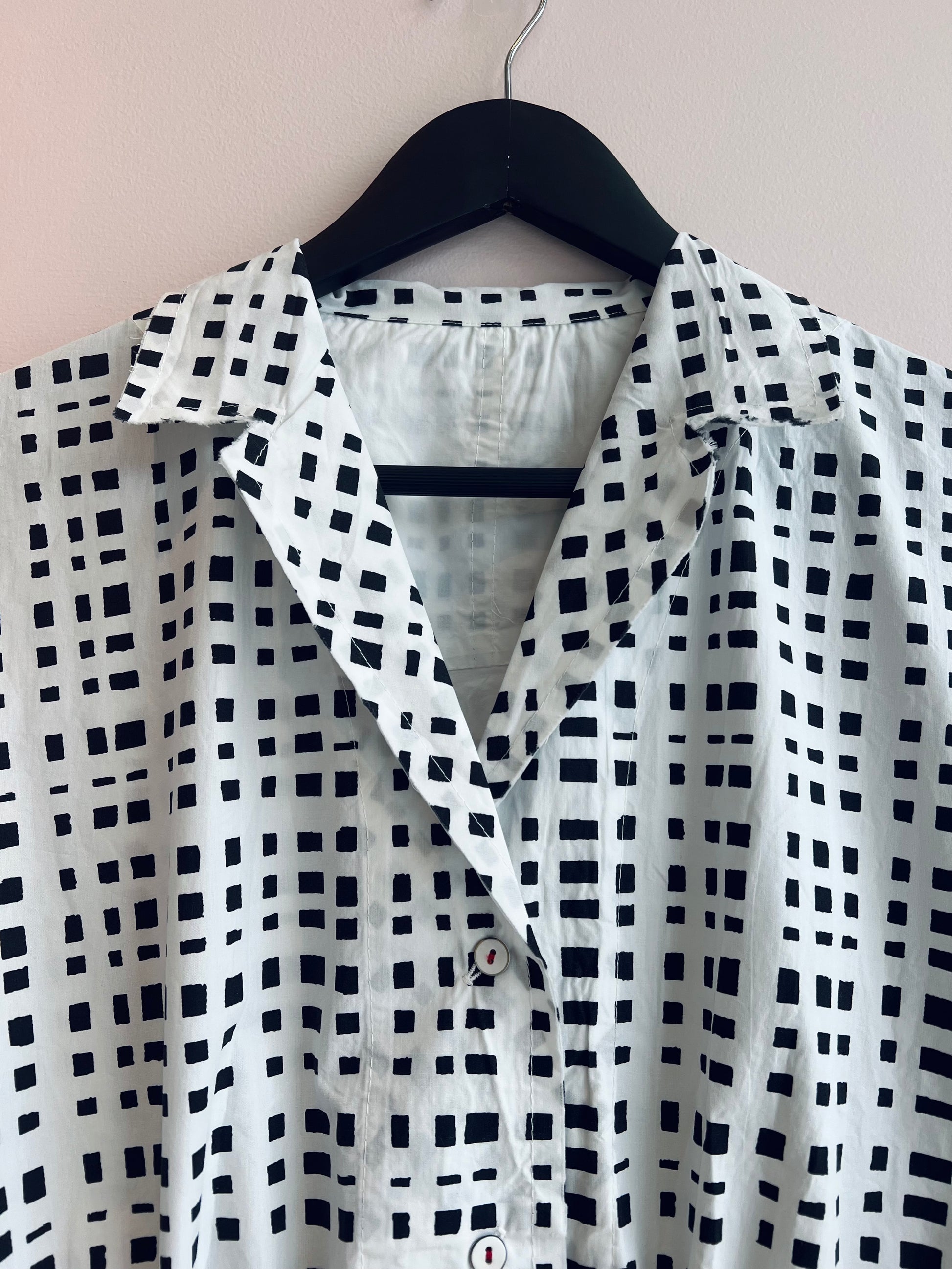 Black and white checkered shirt on a hanger against a beige background