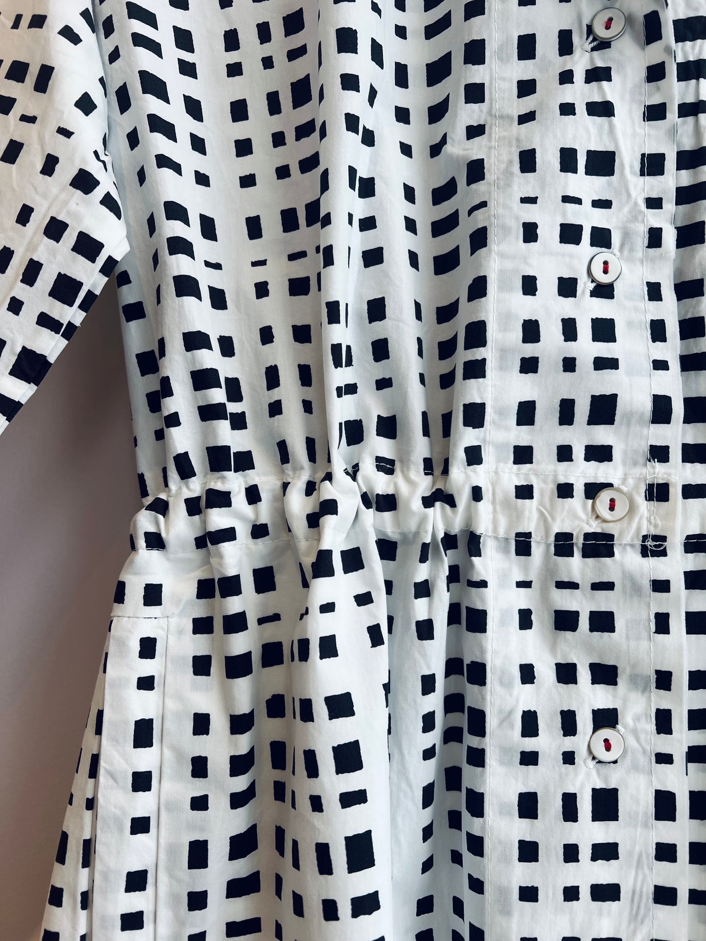 Close-up of a white shirt with black geometric pattern and buttons.