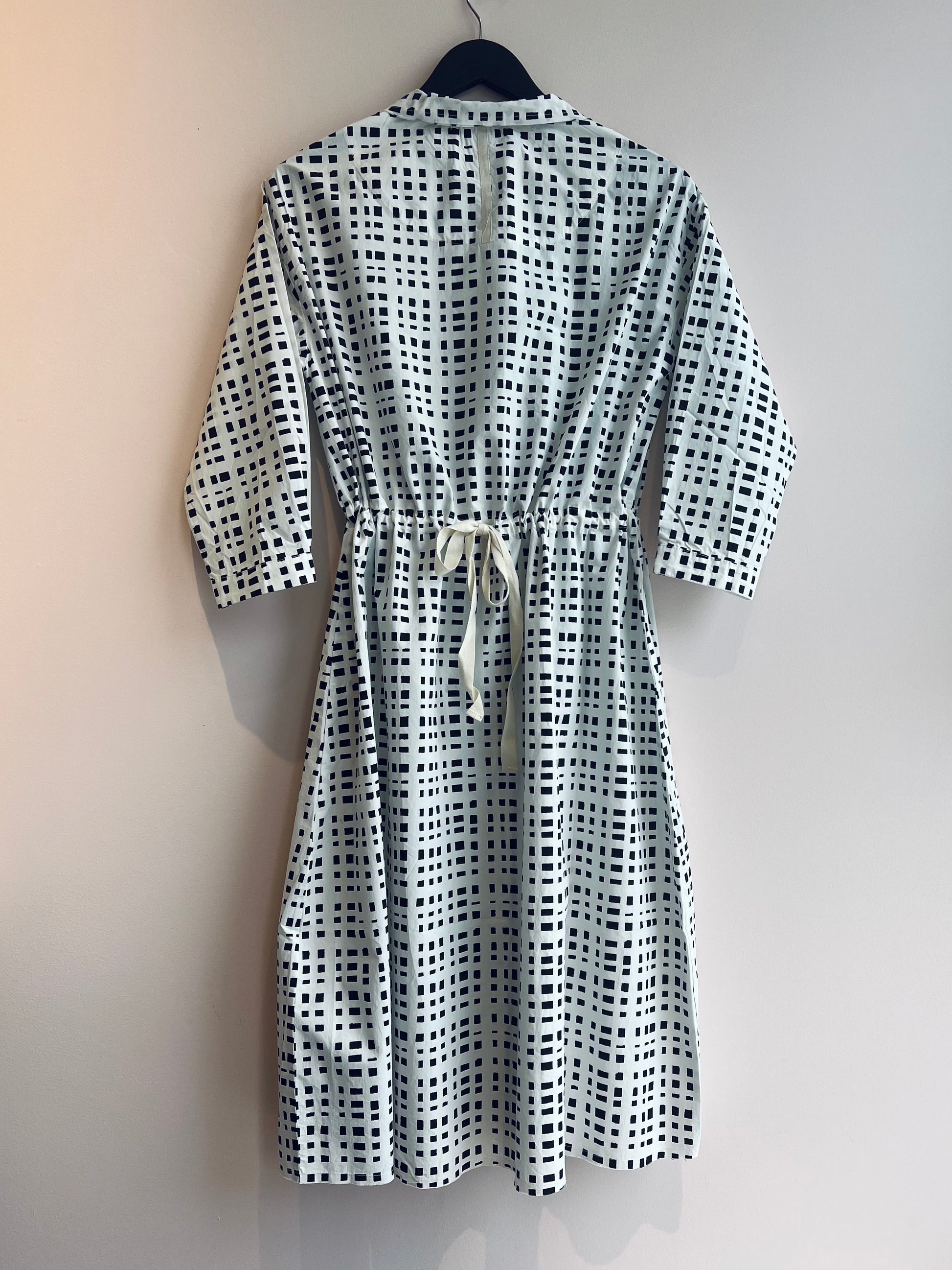 Black and white checkered dress on a hanger against a beige background