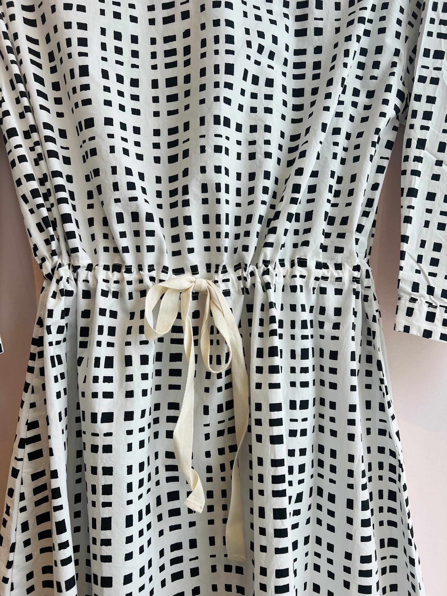 Black and white checkered dress with a drawstring waist on a plain background