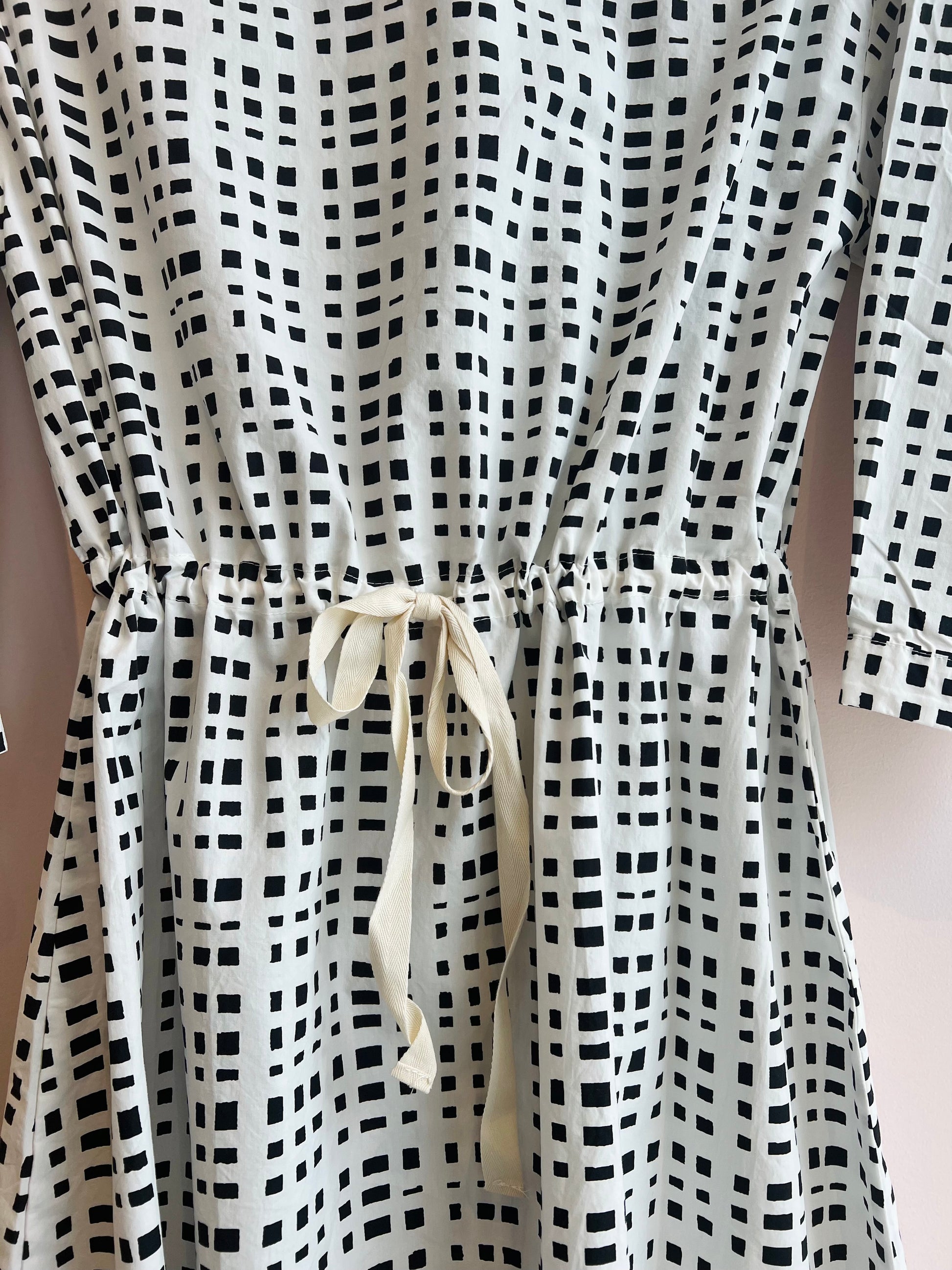 Black and white checkered dress with a drawstring waist on a plain background