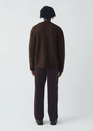 Person wearing a brown sweater and pants on a white background