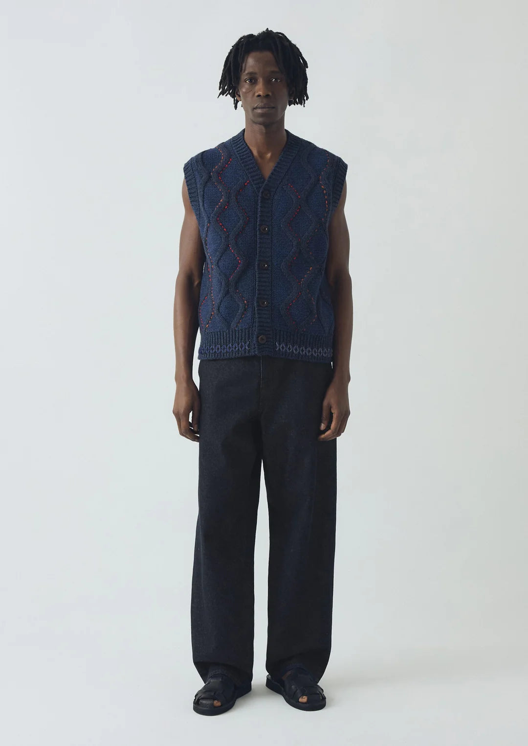 Person wearing a dark blue sleeveless knitted vest on a white background
