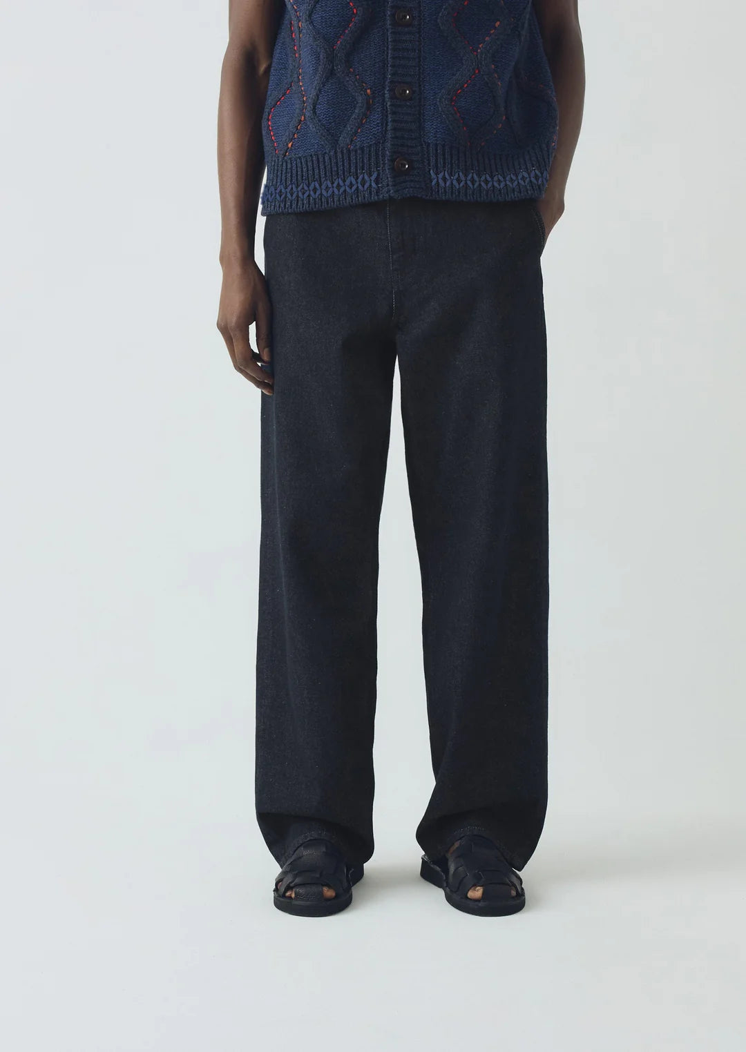 Person wearing a dark blue knitted vest and pants on a white background