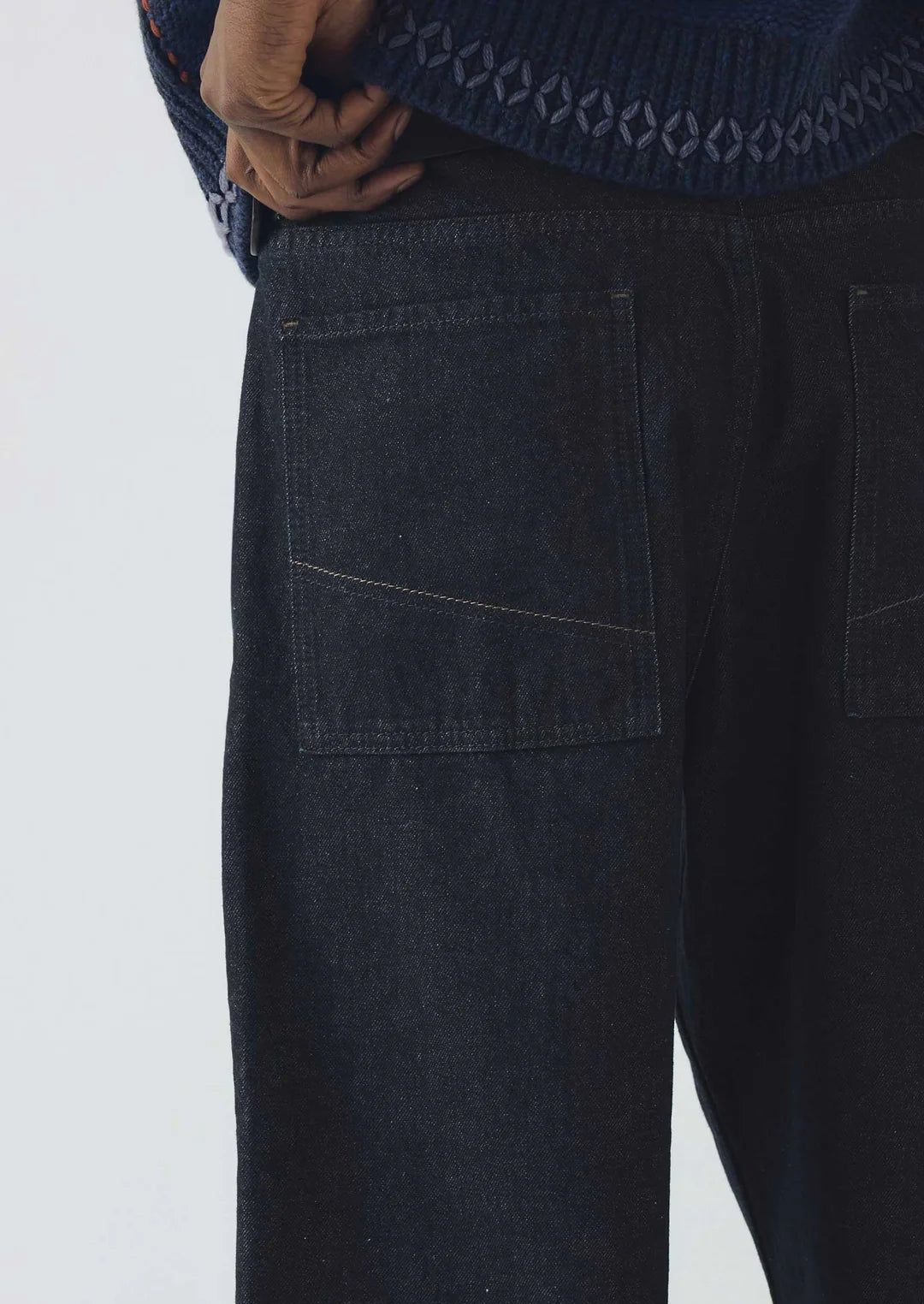Dark blue jeans worn by a person on a white background