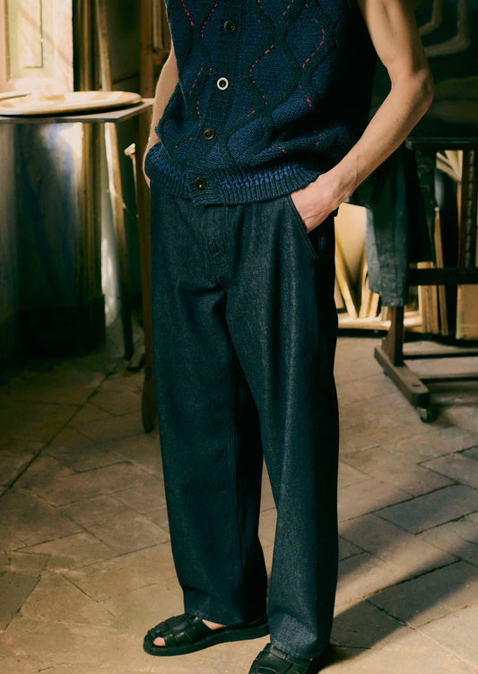 Person wearing a dark blue knitted vest and pants in an indoor setting.