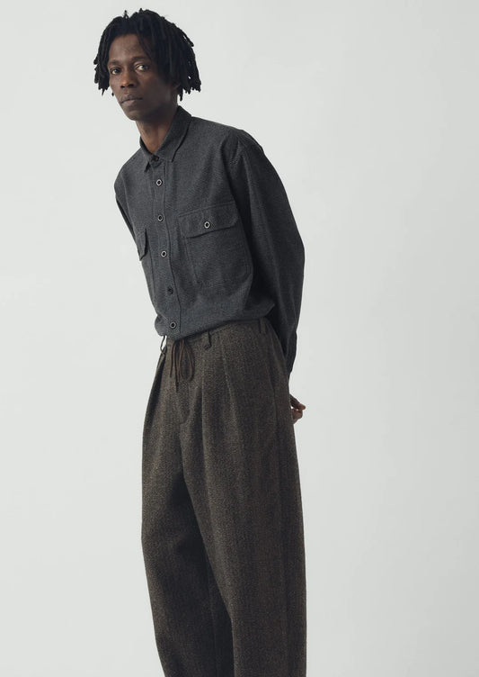 Person wearing a dark gray jacket and matching pants on a white background