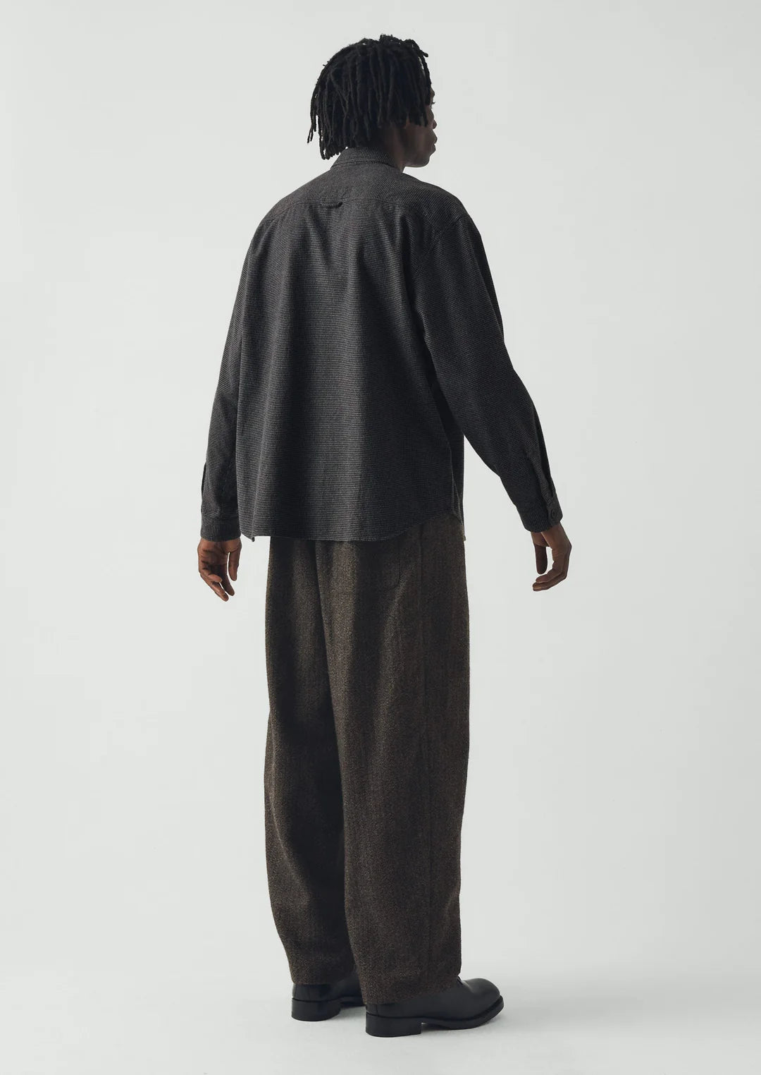 Person wearing a dark gray shirt and brown pants on a white background