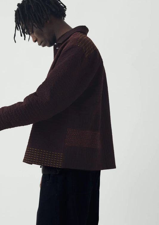 Person wearing a brown textured jacket on a white background