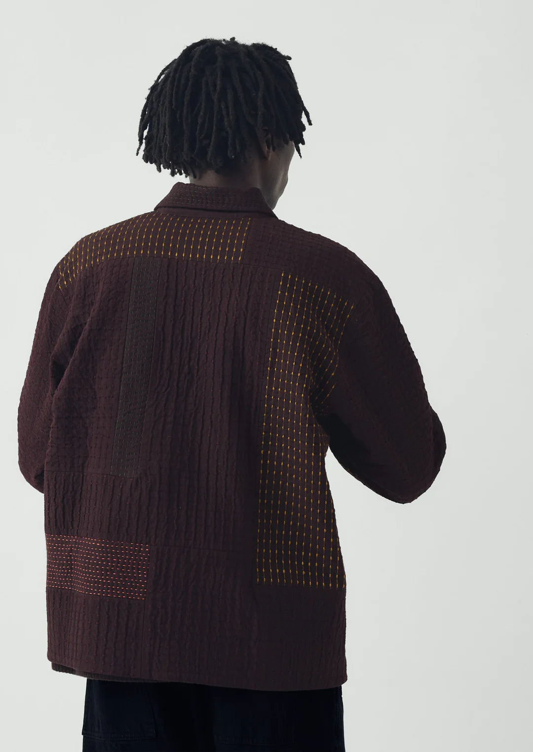 Person wearing a brown textured jacket on a plain background