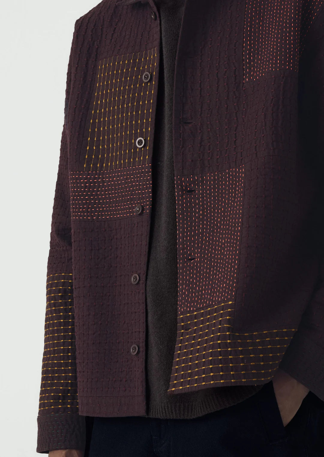 Dark brown textured shirt with patterned patch on a white background