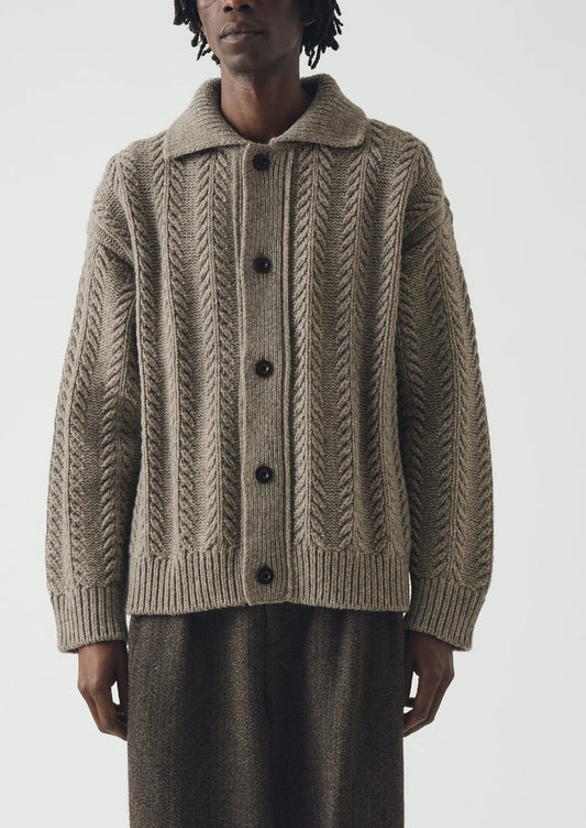 Image of a man wearing a beige colored heavy knitted wool cardigan.