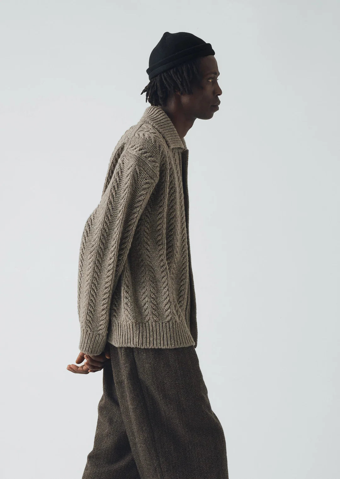 Side view of Image of a man wearing a beige colored heavy knitted wool cardigan.