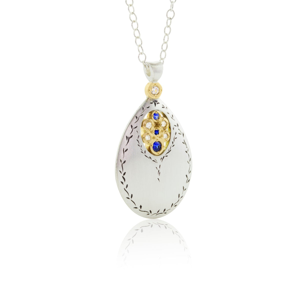 An engraved sterling silver pendant drops with a center of gemstones surrounded by yellow gold.