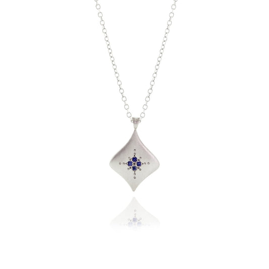 A sterling silver kite-shaped pendant necklace with an etched design and blue sapphires.