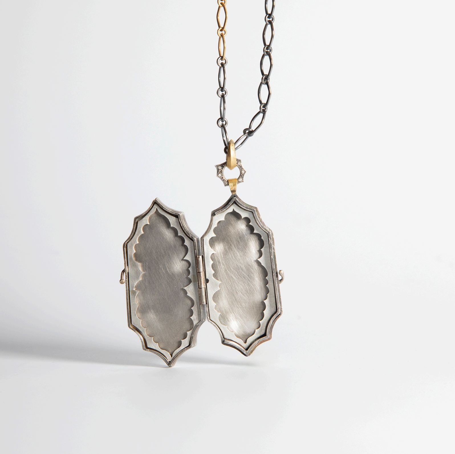 Open locket showing intricate scalloped detail.