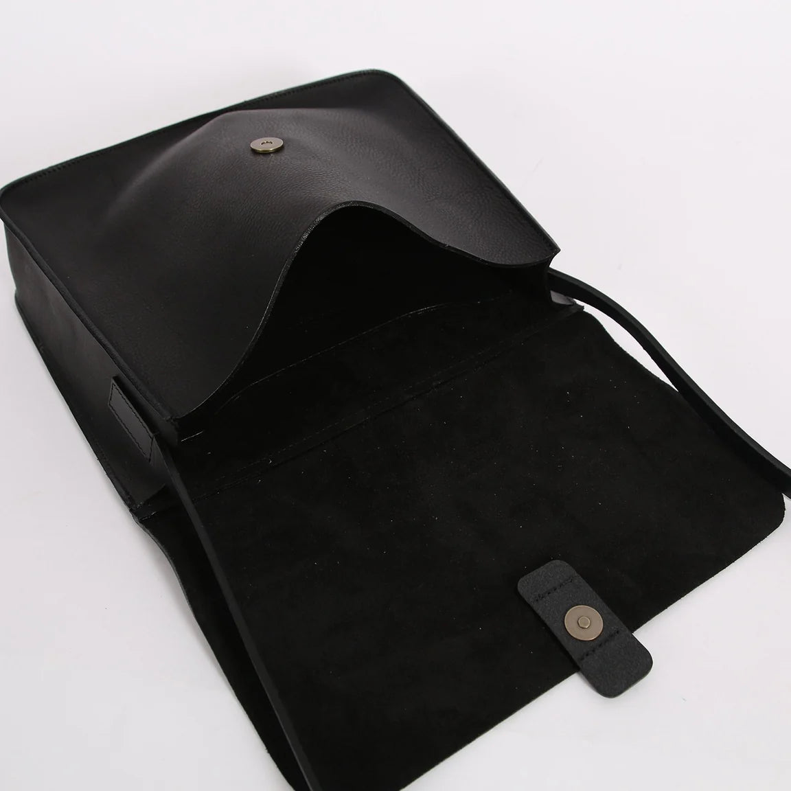 A black leather clutch bag shown open, revealing a black suede-like interior lining and a small gold-tone snap button closure on the flap.