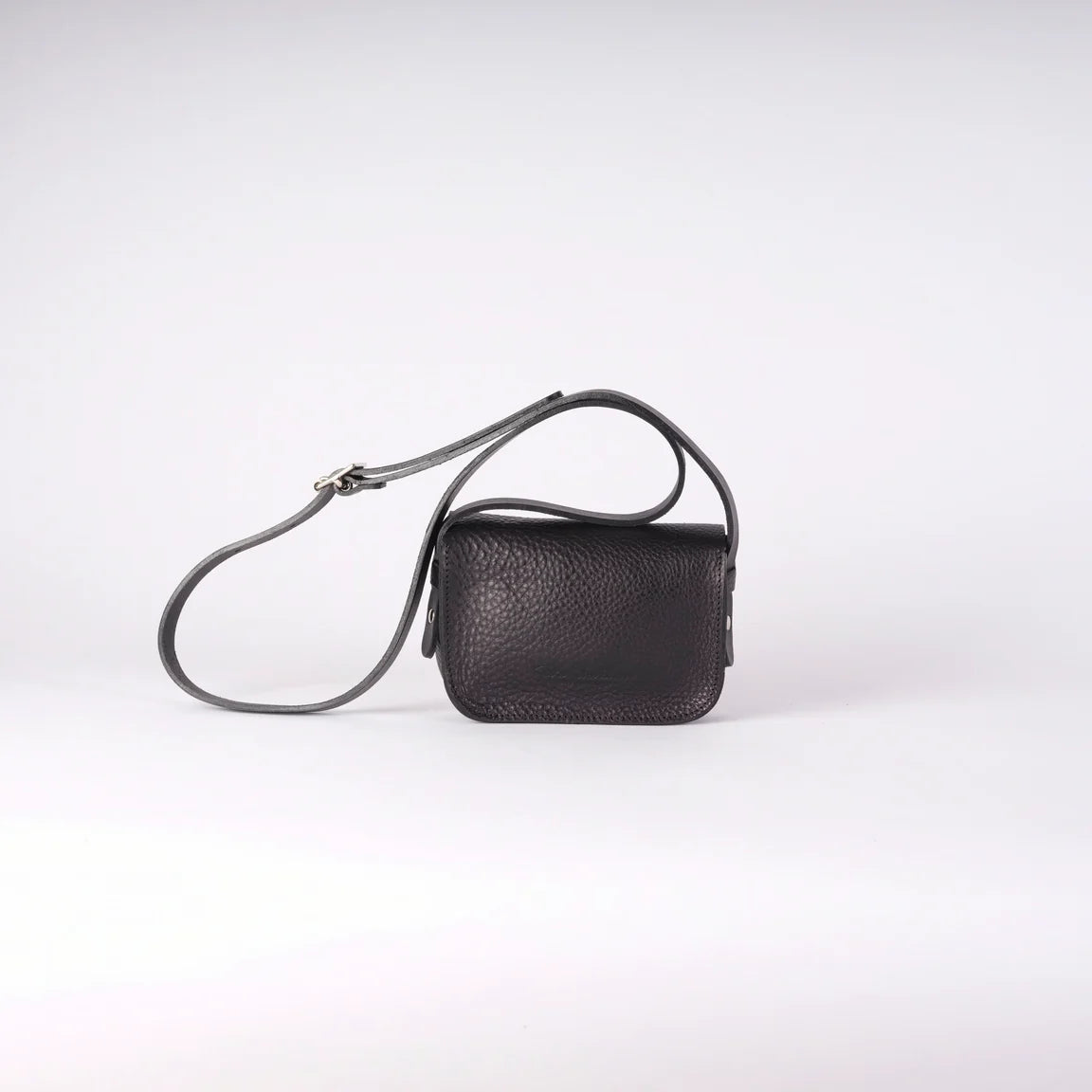 A small black leather crossbody bag with a long adjustable strap, shown on a light gray studio background, reverse view