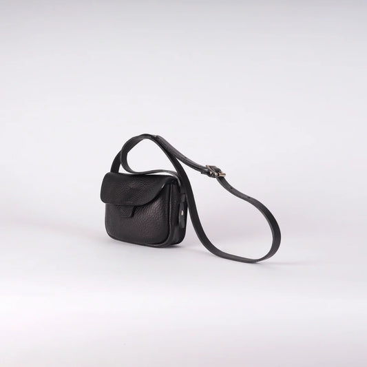 A small black leather crossbody bag with a long adjustable strap, shown on a light gray studio background.