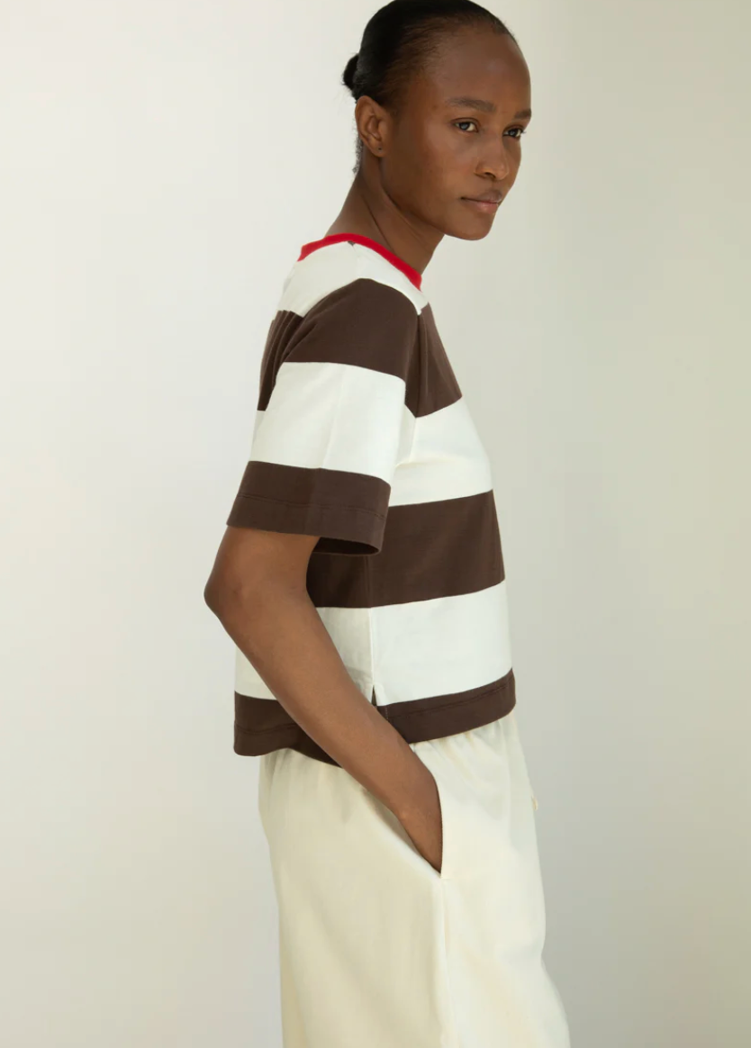 Person wearing a brown and white striped shirt with a red collar against a plain background